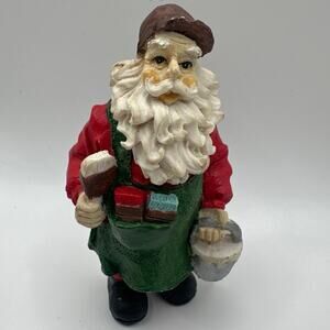 Vintage Santa Clause figurine in brown cap and green apron working/Painting.